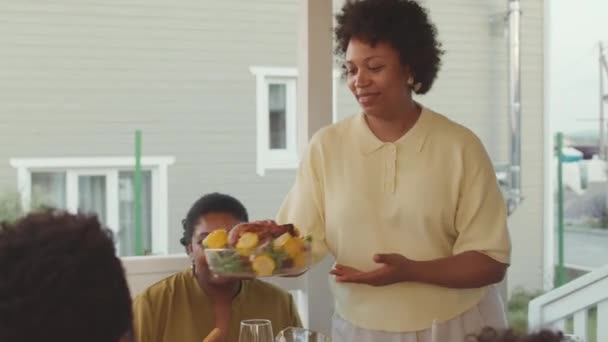Średnie Ujęcie Szczęśliwej Afroamerykanki Serwującej Kolację Przyjaciołom Rodzinie Siedzącej Przy — Wideo stockowe