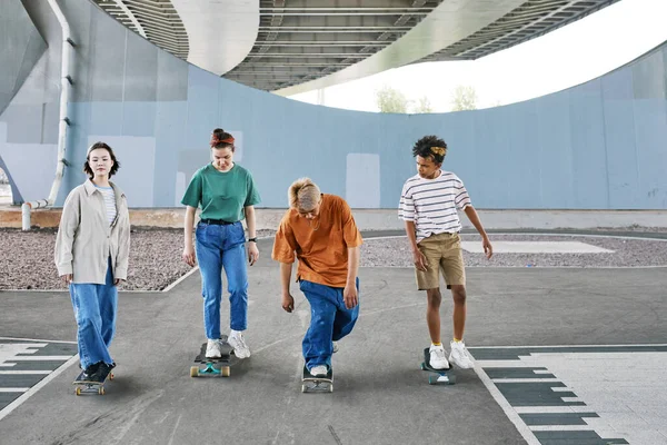 都市スケートエリアでスケートボードに乗っているティーンエイジャーの多様なグループのフルショット コピースペース — ストック写真