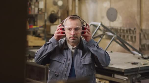 Medium Slowmo Portrait Middle Aged Caucasian Metalworker Taking Safety Headphones — Stockvideo