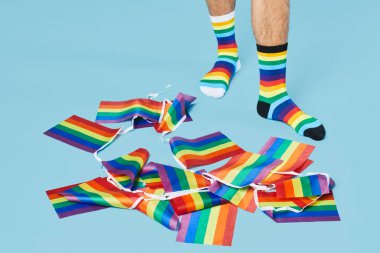 Gökkuşağı çoraplı, pastel mavi arka planda LGBTQ bayraklı bir adamın en düşük görüntüsü, kopyalama alanı