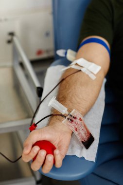 Bağış merkezinde kan verirken bir erkeğin stres topunu sıkması.
