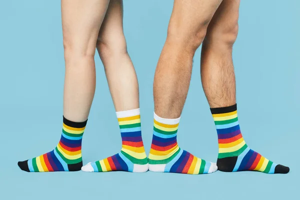Minimal shot of couple wearing rainbow socks on pastel blue background