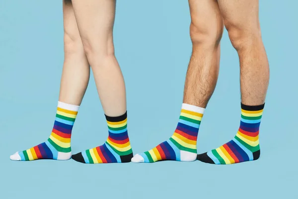 Minimal shot of young couple wearing rainbow socks on pastel blue background