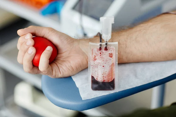 男性手紧紧抓住压力球 同时在医疗义工中心献血 把重点放在血袋上 复制空间 — 图库照片