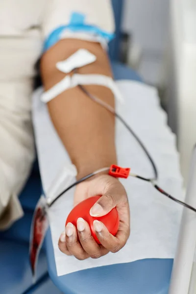 一名身份不明的非洲裔美国妇女躺在献血中心的椅子上献血 她的手捏紧了压力球 — 图库照片