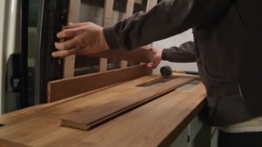 Experienced joiner using hammer while assembling wooden kitchen set inside camper auto