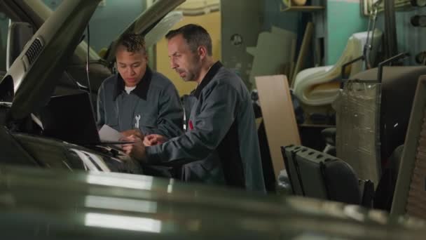 Two Multiethnic Mechanics Standing Camper Van Bonnet Doing Diagnostics Laptop — стоковое видео