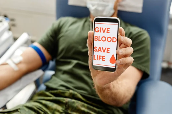 Zbliżenie Żołnierza Oddającego Krew Trzymającego Smartfona Przed Kamerą Daj Krew — Zdjęcie stockowe