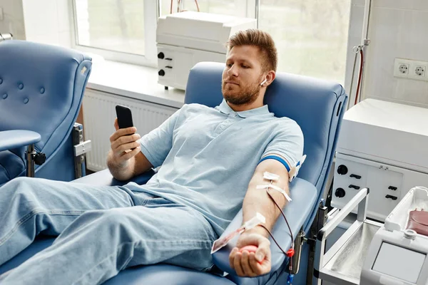 Tıp Merkezinde Rahat Koltukta Yatarken Akıllı Telefon Kullanarak Kan Bağışı — Stok fotoğraf