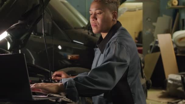 Medium Shot Biracial Female Mechanic Using Laptop While Examining Bonnet — Αρχείο Βίντεο