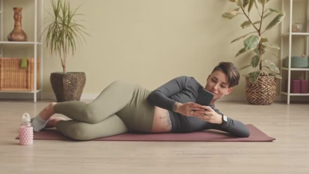 Contemporary Pregnant Woman Texting Smartphone While Lying Relaxedly Yoga Mat — Vídeos de Stock