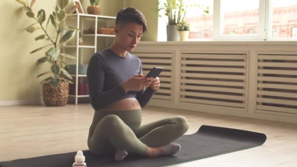 Contemporary Young Pregnant Woman Tight Activewear Using Smartphone While Sitting — Stock Video