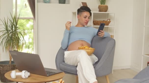 Short Haired Young Pregnant Woman Eating Unhealthy Food While Scrolling — Vídeo de stock