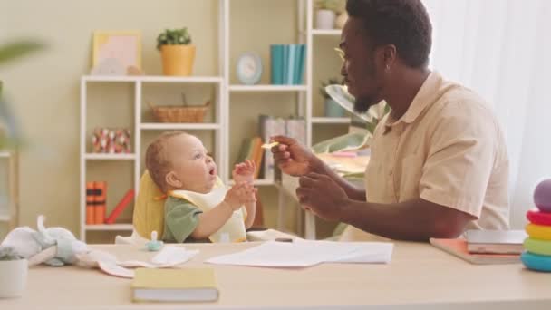 Kochający Afroamerykanin Ojciec Karmi Swojego Słodkiego Synka Domu Siedzi Przy — Wideo stockowe