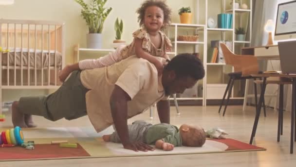 Afroamerikanischer Vater Von Zwei Kleinkindern Macht Liegestütze Hause Mit Hilfe — Stockvideo