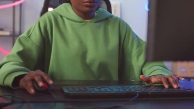 Evde online bilgisayar oyunu oynarken fare ve klavye kullanan heyecanlı genç siyahi kadın
