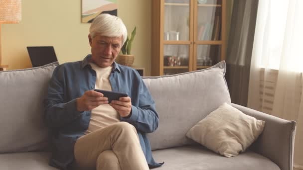 Caucasian Senior Man Playing Games Smartphone While Sitting Couch Home — Stock Video