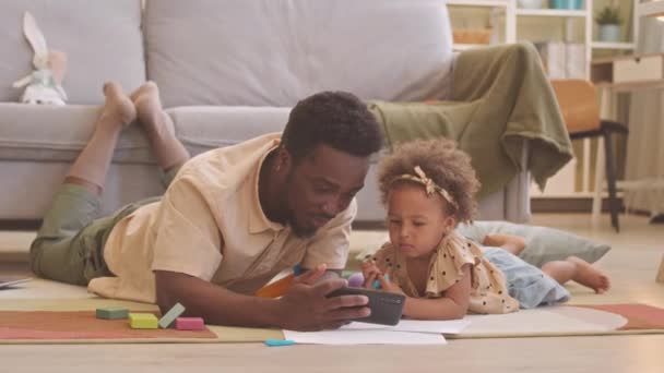 Afroamerikaner Und Seine Hübsche Kleine Tochter Liegen Auf Teppich Wohnzimmer — Stockvideo