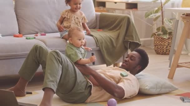 Zärtlicher Junger Afroamerikanischer Mann Der Mit Seinen Zwei Kleinen Kindern — Stockvideo