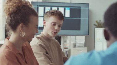 Bir grup genç yaratıcı programcı modern bilişim şirketinde ofis masasında proje tartışıyorlar.