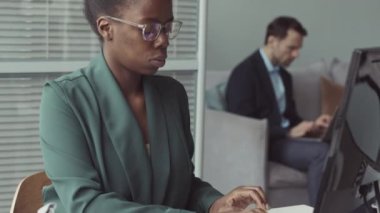 Bilgisayarda yazı yazan ve üzerinde sanal gerçeklik kulaklığı olan Afro-Amerikan kadın yazılım mühendisinin yavaşlığını kaldır.