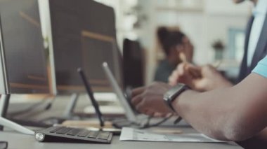 İş arkadaşlarıyla birlikte çalışırken Afrikalı Amerikalı erkek yazılım geliştiricisinin bilgisayarda program kodlarını yazarken yavaş yavaş yaklaş.