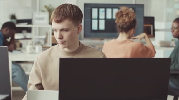 若い白人男性プログラマーは 多様な同僚とItオフィスで働いている間 コンピュータモニターを見ています — ストック動画