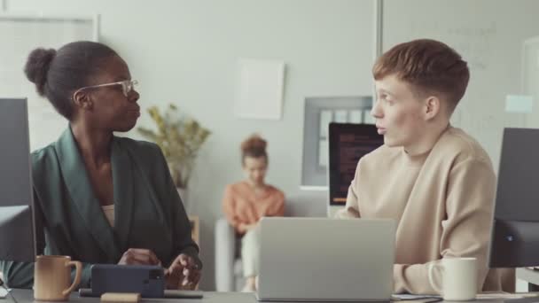 2人の多様な男性と女性プログラマーが 職場のノートパソコンの前に座って会話をする — ストック動画