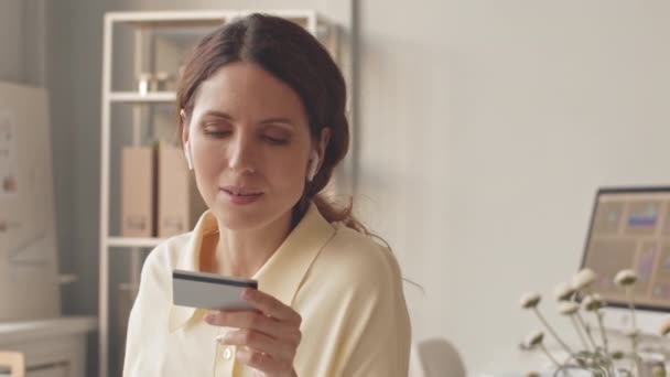 若い美しい女性が緑のスムージーを飲んで 自宅からオンラインショッピングしながら ウェブサイト上の彼女のクレジットカードから情報を入力 — ストック動画