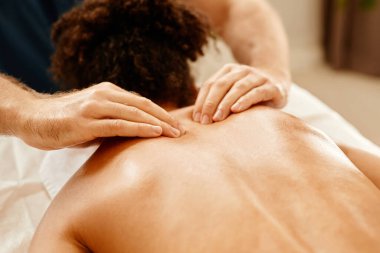 Sağlık kulübündeki SPA seansından zevk alan genç bir kadının sırt ve omuzlarına masaj yapan erkek ellerini kapat.