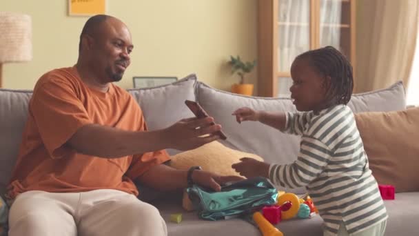 Hombre Negro Mostrando Pantalla Del Teléfono Inteligente Linda Hija Pequeño — Vídeos de Stock