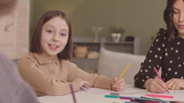 İlkokul kızı ve ailesi Hanuka 'da evde masa başında kartpostal çiziyorlardı.