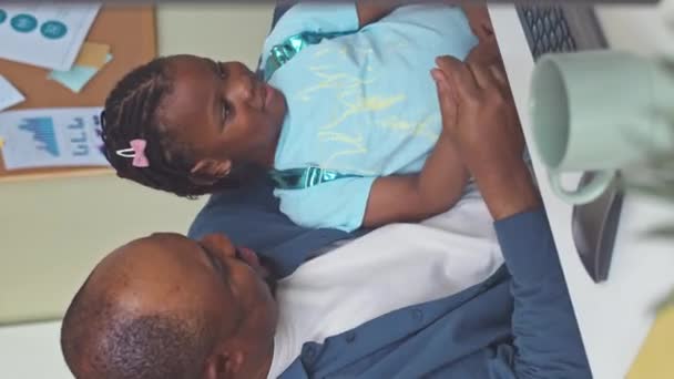 Ofiste Çalışırken Küçük Kızıyla Oynayan Neşeli Siyahi Adamın Dikey Çekimi — Stok video