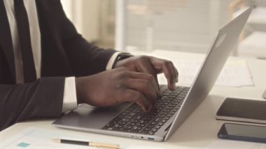 Ofiste çalışırken dizüstü bilgisayarda yazı yazan siyahi işadamı.