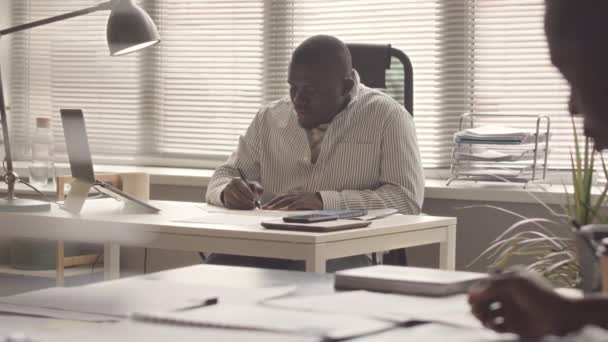 Σοβαρός Αφροαμερικάνος Επιχειρηματίας Που Συμπληρώνει Οικονομικά Έγγραφα Που Βρίσκονται Στο — Αρχείο Βίντεο