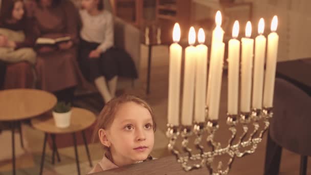 Dívka Dívá Zájmem Zapálené Svíčky Menorah Stojící Tmavém Obývacím Pokoji — Stock video