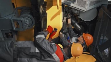 Tesiste traktörü tamir ederken ekipte çalışan çok ırklı mühendis çiftinin dikey çekimi