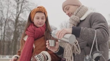 Termostan çay içen ve kış tatillerinde buz pateni pistinde romantik bir buluşma sırasında sohbet eden beyaz bir çift.