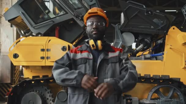 男工头戴硬帽 戴安全帽 头戴制服 站在爬山机旁拍照的黑人男性工厂工人肖像 — 图库视频影像