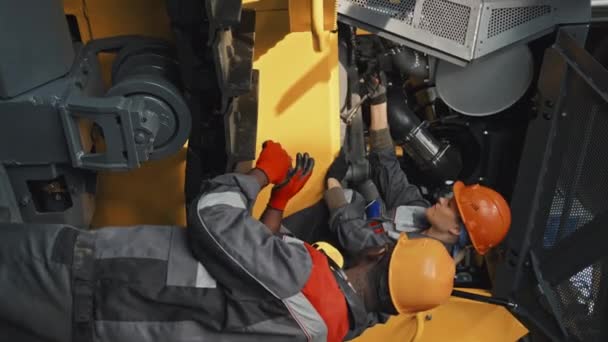 Zdjęcie Pionowe Wieloetnicznej Pary Mechaników Pracujących Zespole Podczas Naprawy Ciągnika — Wideo stockowe
