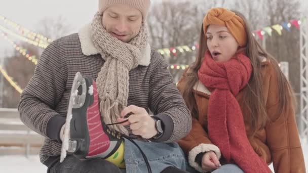Jovem Cuidando Sua Namorada Durante Data Pista Gelo Amarrando Cadarços — Vídeo de Stock