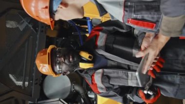 Siyahi adamın kadın meslektaşıyla konuşurken, traktör fabrikasında mühendis olarak çalışırken çekilmiş dikey görüntüsü.