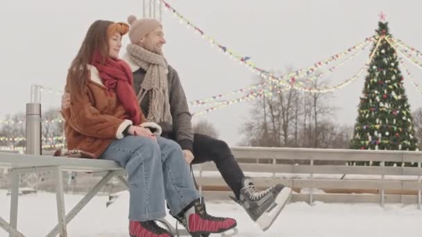 Jovem Casal Afetuoso Divertindo Enquanto Prepara Para Patinação Gelo Sentado — Vídeo de Stock