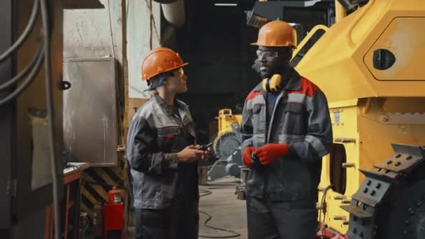 Средний Снимок Двух Мужчин Женщин Работающих Тракторном Заводе Касках Комбинезонах — стоковое видео