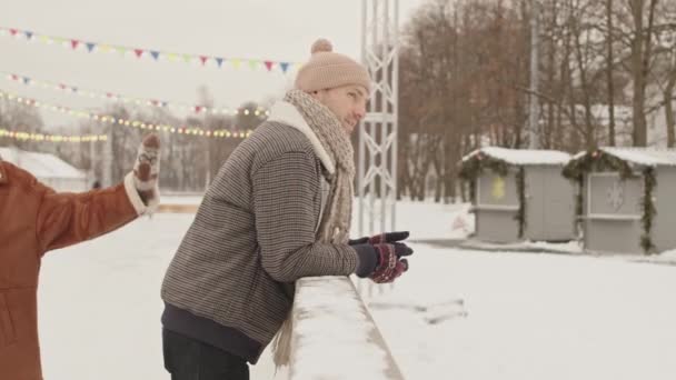 年轻的白种人情侣在溜冰后休息的时候靠在户外冰场边聊天 — 图库视频影像