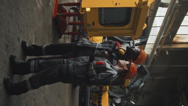 Verticaal Schot Van Twee Verschillende Trekkerfabrieksarbeiders Overalls Harde Hoeden Die — Stockvideo