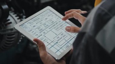 Fabrika üretim makinelerinde çalışırken tablet bilgisayarda teknik şemayı inceleyen tanınmayan mühendis