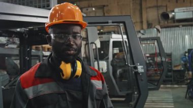 Afrika kökenli Amerikalı bir adamın makine ekipman üretim tesisinde çalışırken, iş yerinde gezinti yaparken kameraya konuşma görüntüsü.
