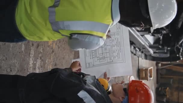 Vertikale Aufnahme Zweier Multiethnischer Ingenieure Harten Hüten Die Technische Zeichnungen — Stockvideo