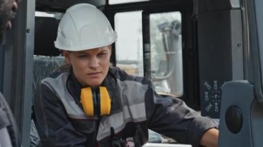 Üniformalı iki kadın ve erkek teknoloji mühendisi fabrikada makine ekipmanı kuruyor.